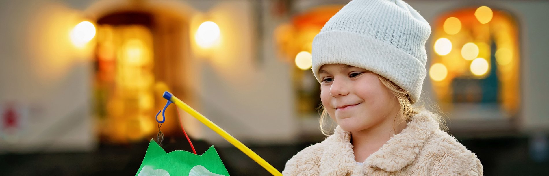 Little preschool kid girl holding selfmade traditional owl lanterns with candle for St. Martin procession. child happy about children and family parade in kindergarten. German tradition Martinsumzug
